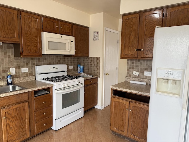 kitchen with tasteful backsplash, sink, white appliances, and light wood-type flooring