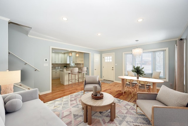 living room featuring ornamental molding, an inviting chandelier, and light hardwood / wood-style floors