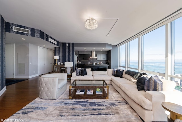 living room featuring wood finished floors, visible vents, baseboards, wallpapered walls, and an inviting chandelier