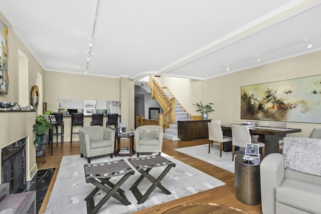 living room with hardwood / wood-style floors, rail lighting, ornamental molding, and a premium fireplace