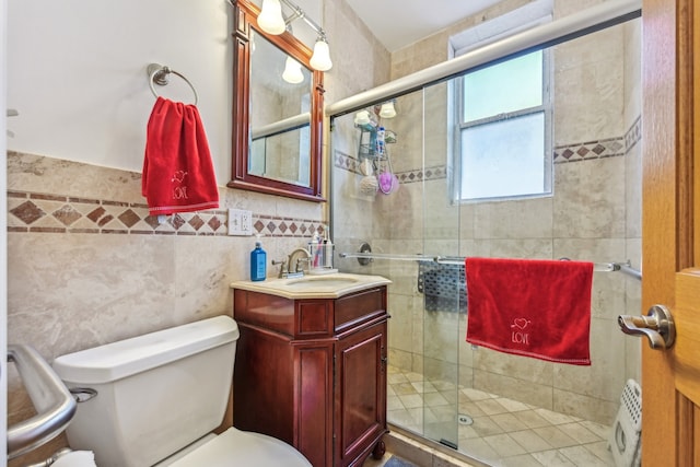 bathroom featuring vanity, toilet, tile walls, and walk in shower