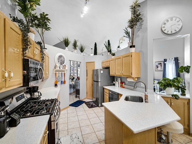 kitchen featuring a towering ceiling, appliances with stainless steel finishes, light tile patterned floors, a kitchen breakfast bar, and sink