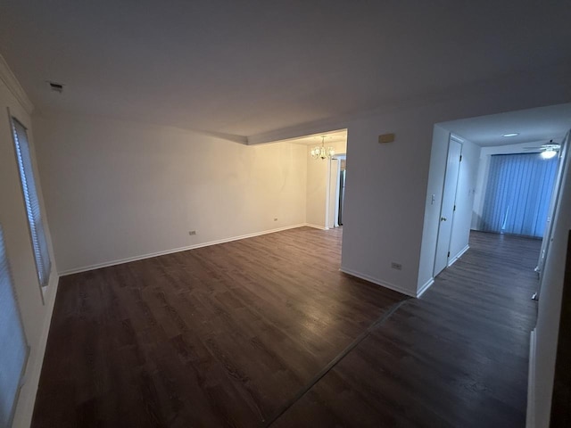 spare room with ceiling fan with notable chandelier and dark wood-type flooring