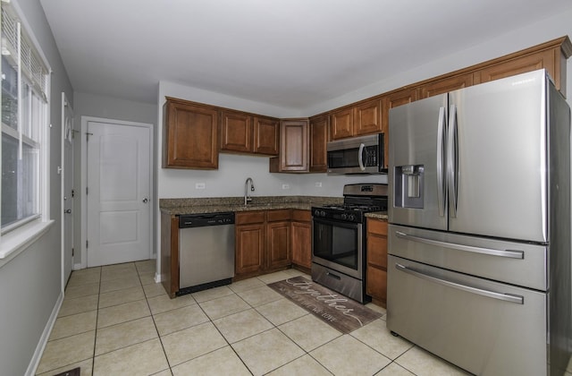 kitchen featuring sink, a wealth of natural light, stainless steel appliances, and dark stone countertops