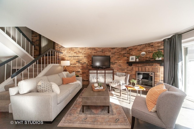 living room featuring brick wall, a wealth of natural light, and a fireplace