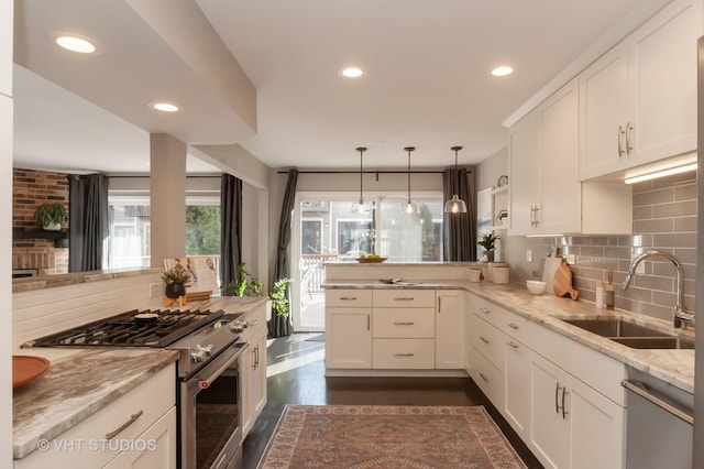 kitchen featuring white cabinetry, sink, light stone counters, kitchen peninsula, and stainless steel appliances