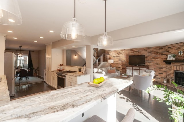 kitchen with appliances with stainless steel finishes, a kitchen breakfast bar, pendant lighting, brick wall, and a fireplace