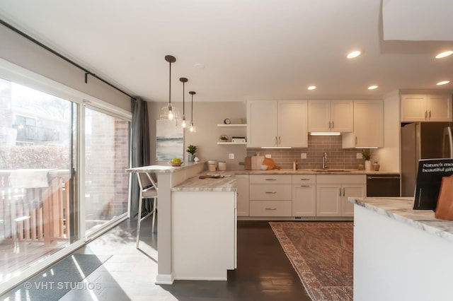 kitchen featuring white cabinetry, sink, light stone counters, and decorative light fixtures