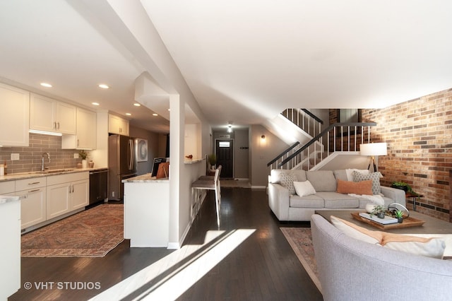 living room with brick wall, dark hardwood / wood-style flooring, and sink