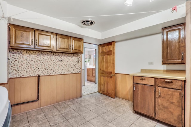 4850 N Crescent Ave, Norridge, IL 60706 - kitchen featuring brown cabinetry, visible vents, wooden walls, a wainscoted wall, and light countertops