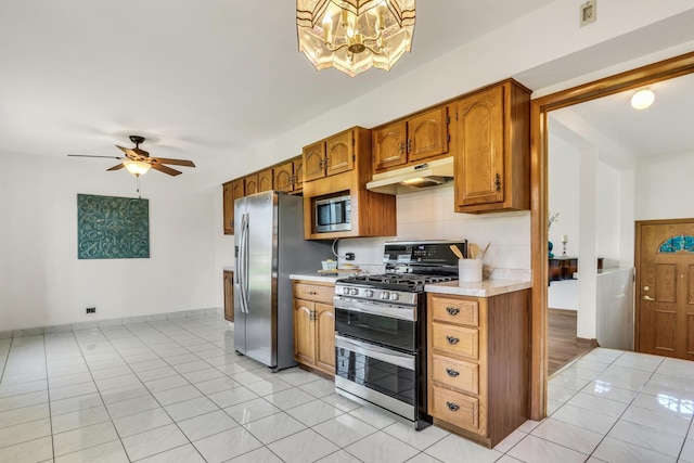 4850 N Crescent Ave, Norridge, IL 60706 - kitchen featuring under cabinet range hood, ceiling fan with notable chandelier, light countertops, tasteful backsplash, and appliances with stainless steel finishes