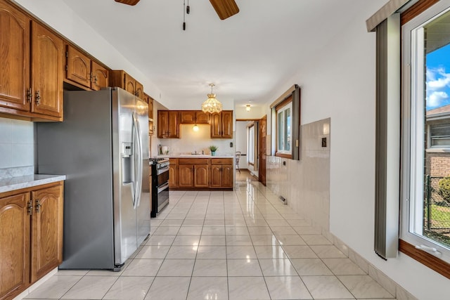 4850 N Crescent Ave, Norridge, IL 60706 - kitchen featuring stainless steel appliances, light tile patterned floors, ceiling fan with notable chandelier, brown cabinets, and light countertops