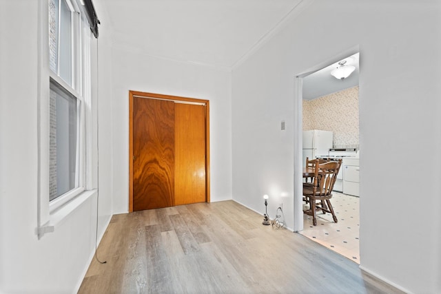 hallway featuring ornamental molding and light hardwood / wood-style floors