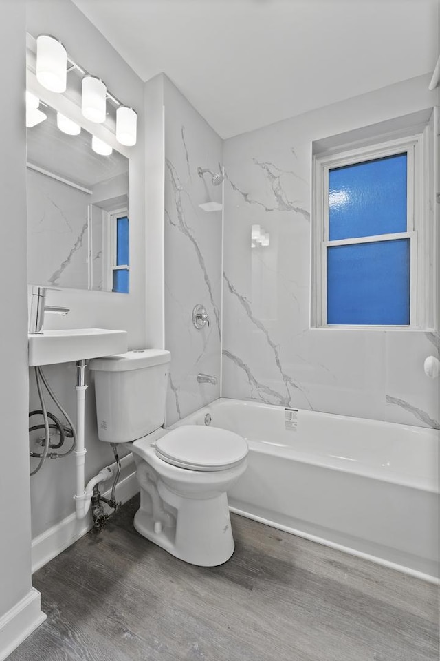 full bathroom with hardwood / wood-style flooring, sink, washtub / shower combination, and toilet