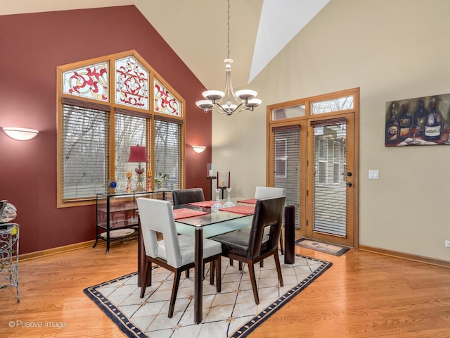 dining space featuring high vaulted ceiling, a notable chandelier, and light hardwood / wood-style floors