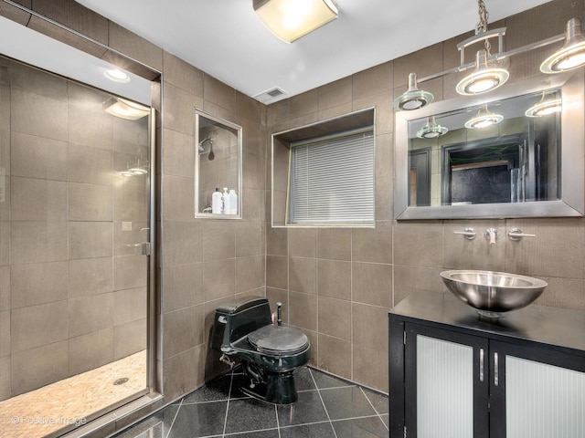 bathroom featuring tile patterned floors, vanity, tile walls, and a shower