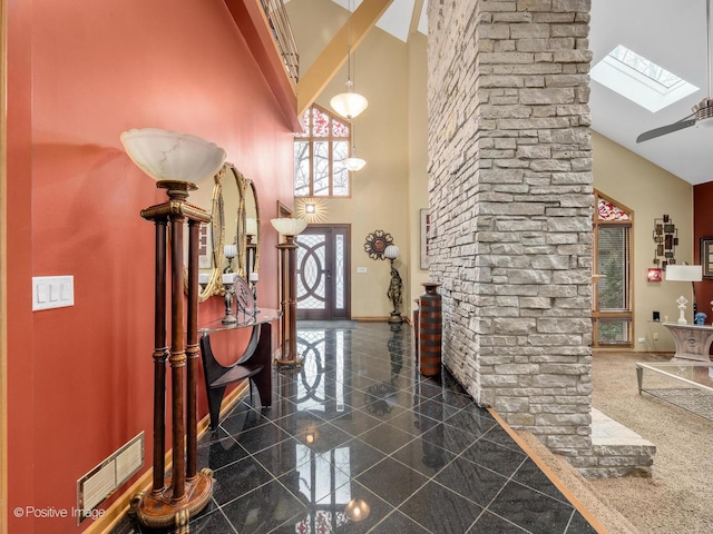 foyer entrance with a towering ceiling and a skylight