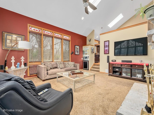 carpeted living room with a skylight, high vaulted ceiling, and ceiling fan