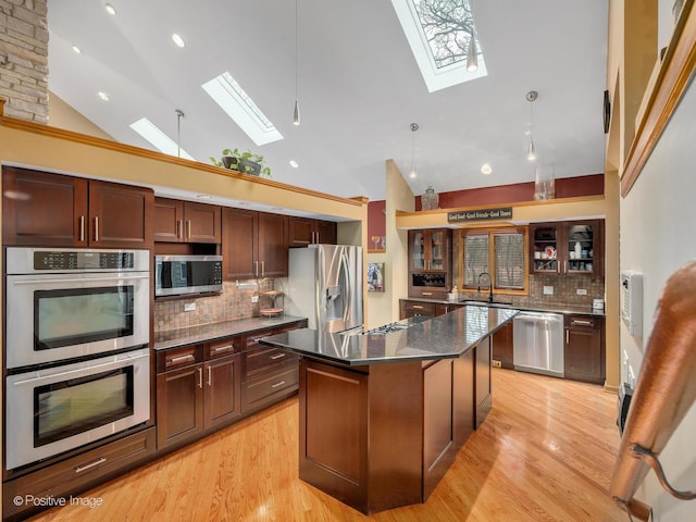 kitchen with stainless steel appliances, a skylight, a kitchen island, and backsplash