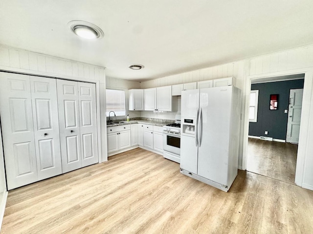 kitchen with white cabinetry, white appliances, light hardwood / wood-style floors, and sink