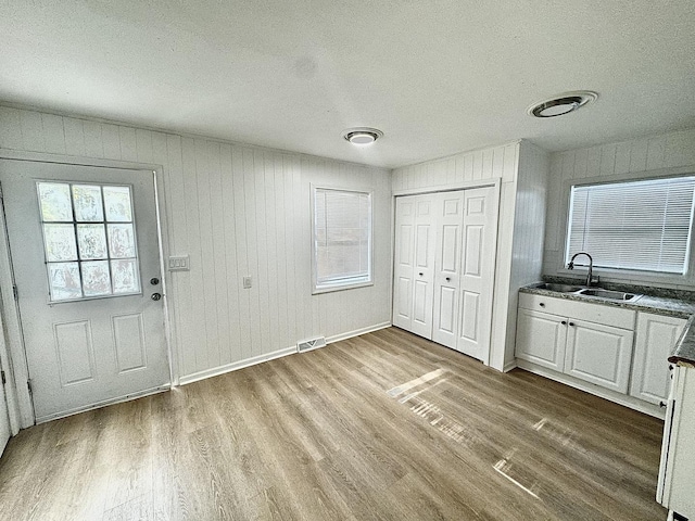 interior space featuring sink, a textured ceiling, light hardwood / wood-style flooring, and wooden walls