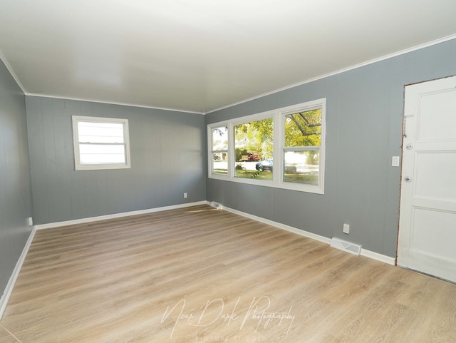 spare room featuring crown molding and light hardwood / wood-style floors