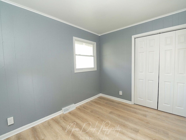 unfurnished bedroom featuring ornamental molding, a closet, and light wood-type flooring