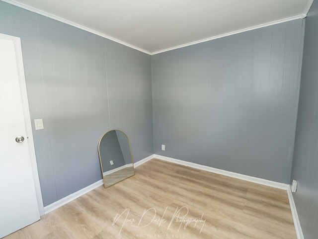 spare room featuring ornamental molding and light hardwood / wood-style flooring