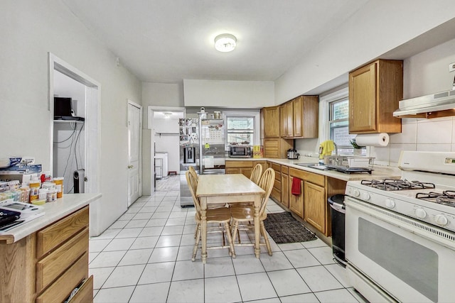 kitchen featuring decorative backsplash, sink, light tile patterned floors, and stainless steel appliances