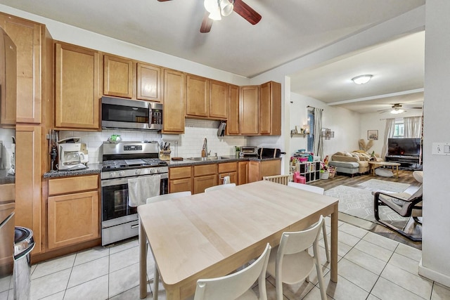 kitchen featuring sink, backsplash, light tile patterned floors, and stainless steel appliances