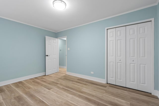 unfurnished bedroom featuring crown molding, light hardwood / wood-style floors, and a closet