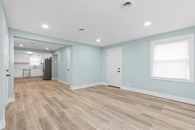 unfurnished living room featuring sink and light wood-type flooring