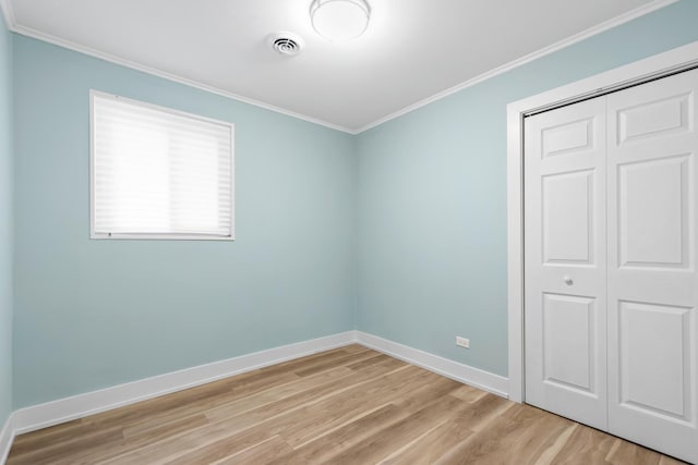 unfurnished bedroom featuring a closet, light wood-type flooring, and crown molding