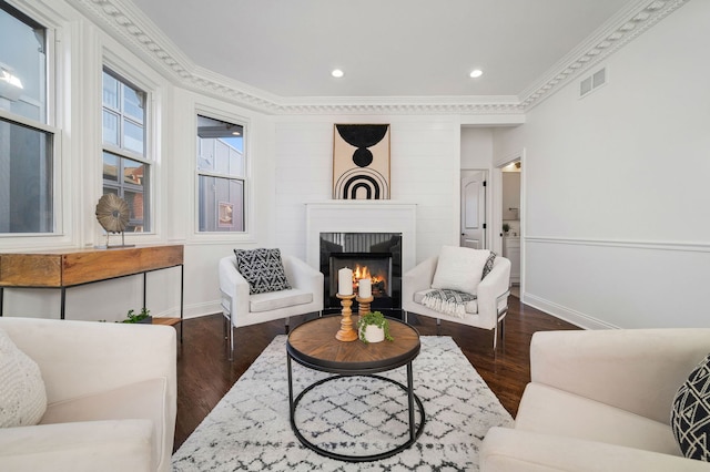 living room featuring ornamental molding, a large fireplace, and dark hardwood / wood-style flooring