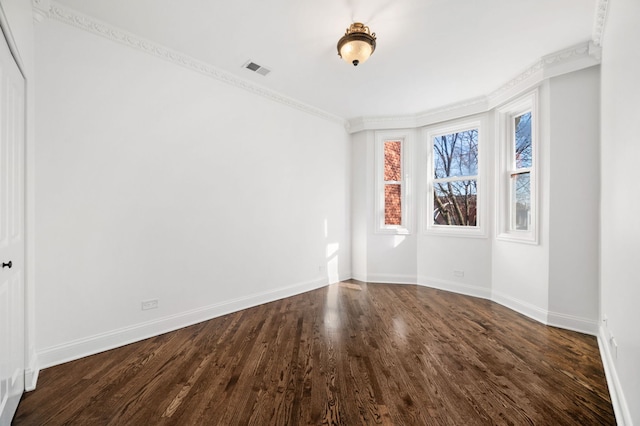 empty room featuring ornamental molding and dark hardwood / wood-style flooring