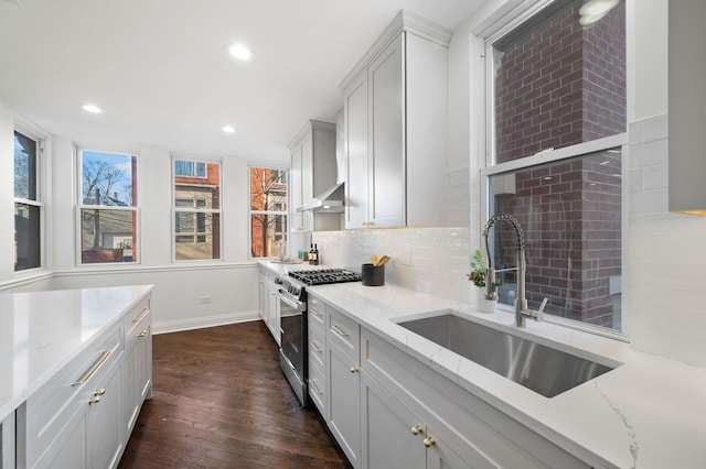 kitchen featuring tasteful backsplash, gas stove, sink, and light stone counters