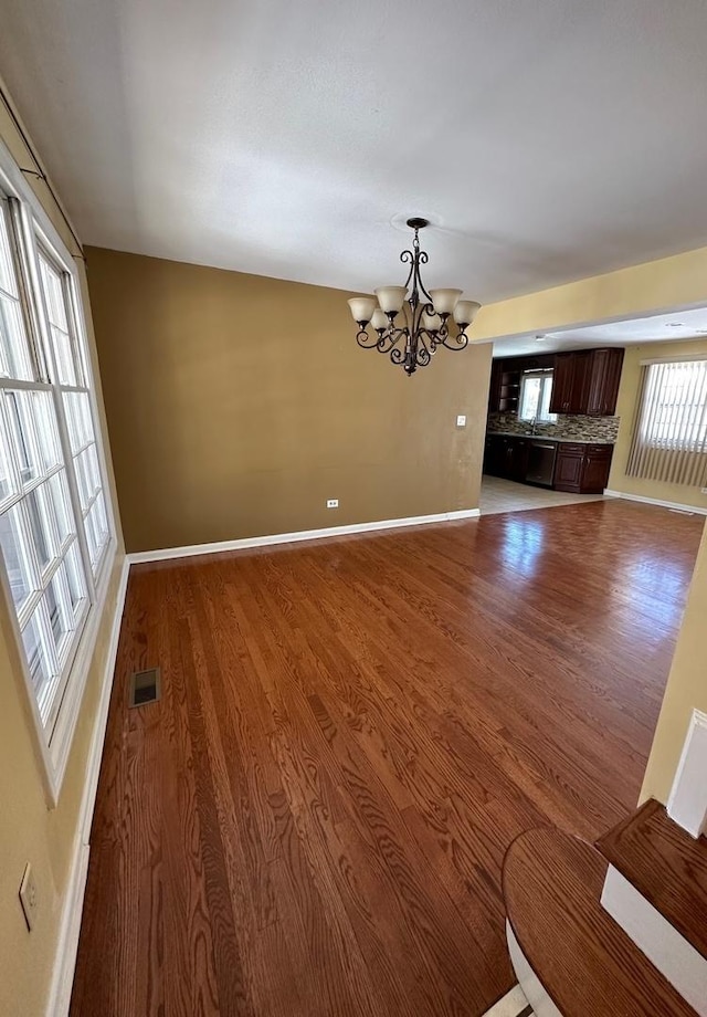 unfurnished living room with hardwood / wood-style flooring and a chandelier