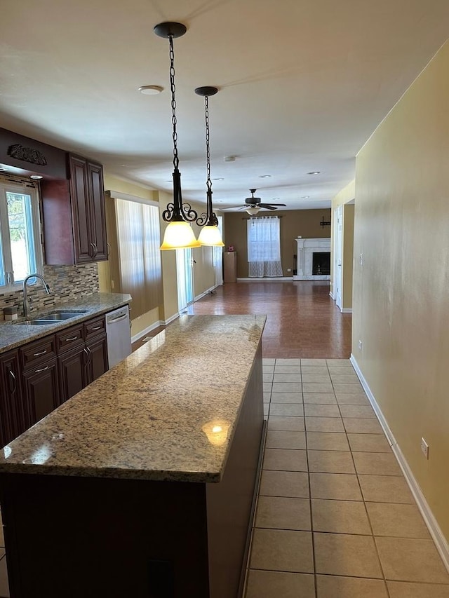 kitchen featuring a kitchen island, pendant lighting, dishwasher, sink, and backsplash