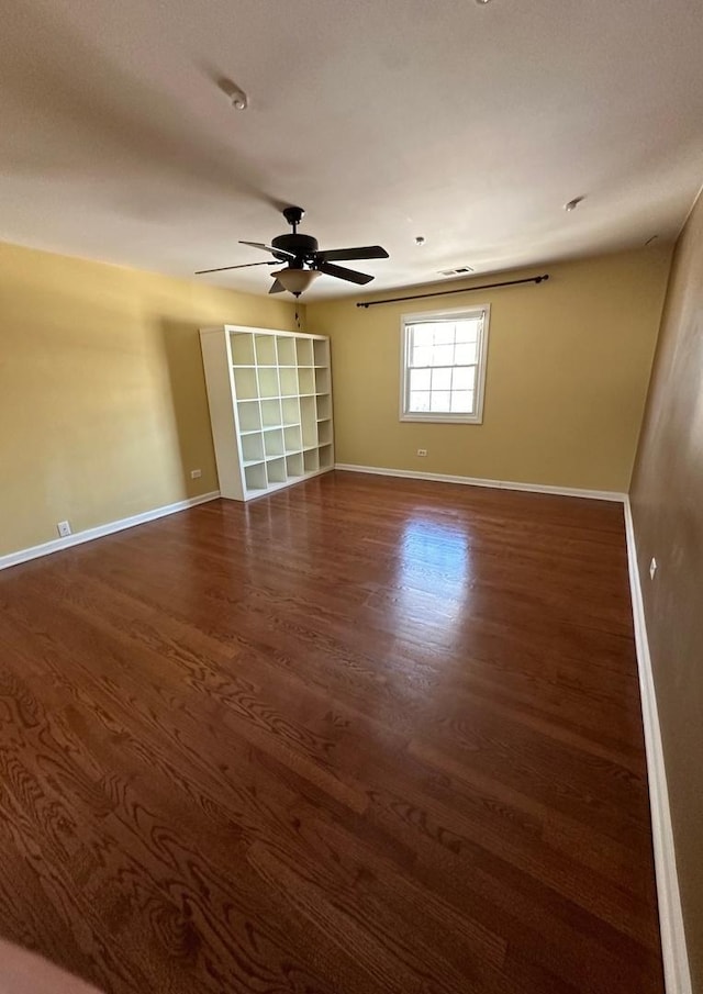 unfurnished room featuring dark wood-type flooring and ceiling fan