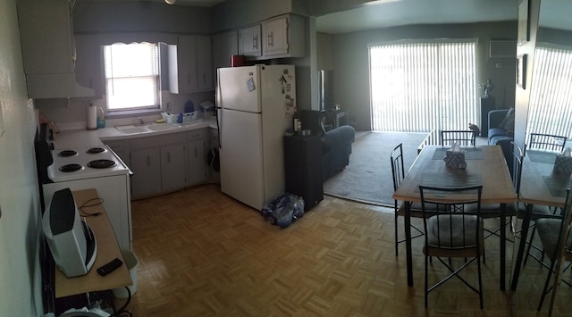 kitchen with sink, white refrigerator, white cabinets, light parquet flooring, and backsplash