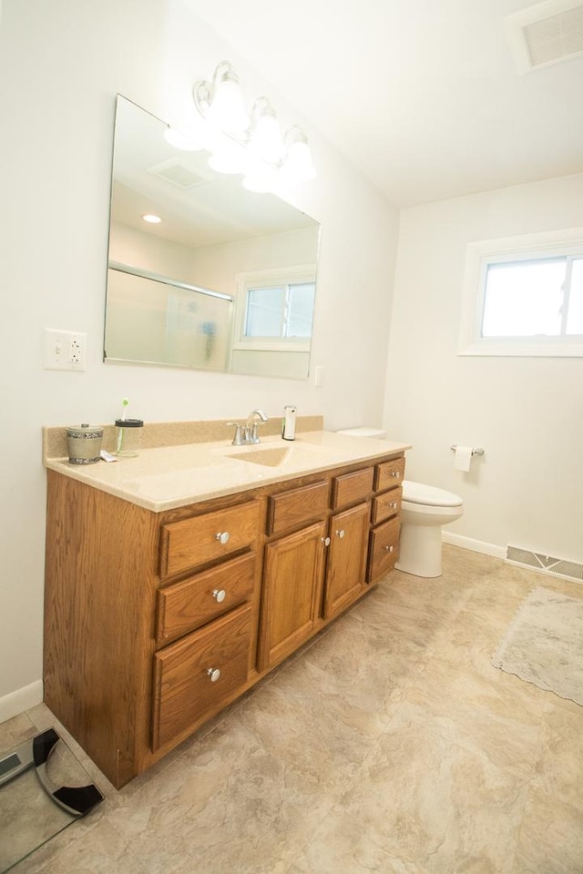 bathroom featuring a shower with door, vanity, and toilet