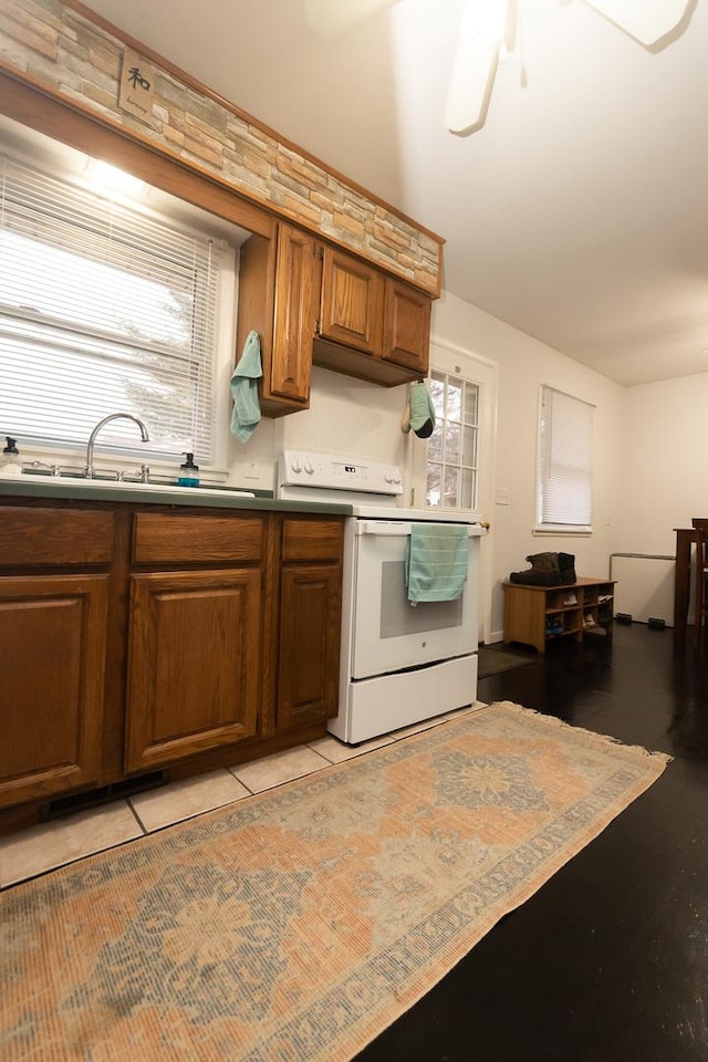 kitchen featuring sink, light tile patterned floors, white electric stove, and ceiling fan