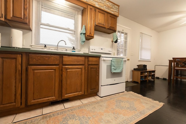 kitchen with white range with electric cooktop, light tile patterned floors, and a wealth of natural light