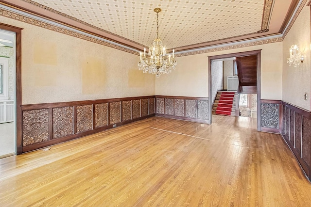 empty room with crown molding, hardwood / wood-style floors, and a notable chandelier