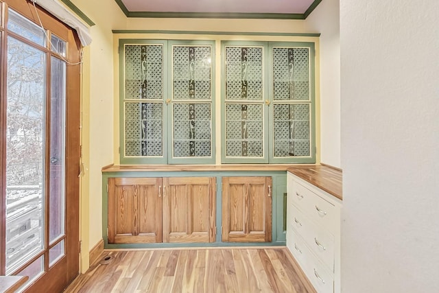 interior space with light hardwood / wood-style flooring, ornamental molding, and a healthy amount of sunlight