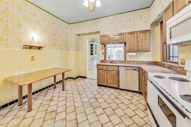 kitchen featuring sink, tile walls, light tile patterned floors, crown molding, and white appliances