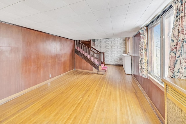 unfurnished room featuring light hardwood / wood-style flooring, radiator heating unit, and wood walls