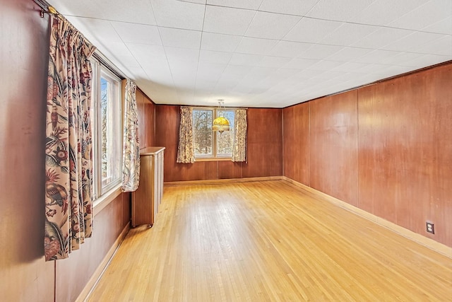 unfurnished room with light hardwood / wood-style flooring and wood walls