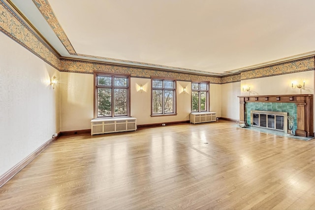 unfurnished living room with radiator heating unit, ornamental molding, hardwood / wood-style floors, and a fireplace