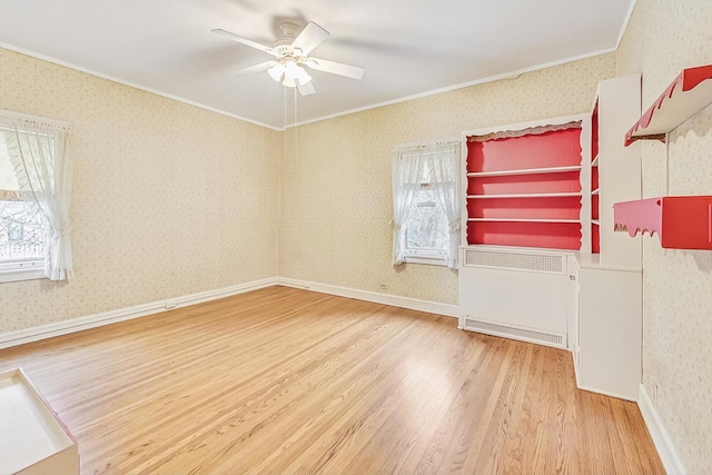 empty room featuring ceiling fan, ornamental molding, radiator heating unit, and hardwood / wood-style floors